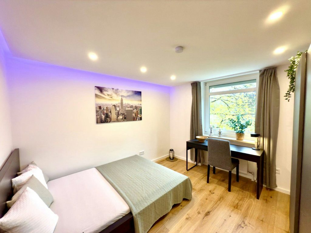 Schlafbereich mit Bett, Arbeitsplatz und Fenster zur Straße